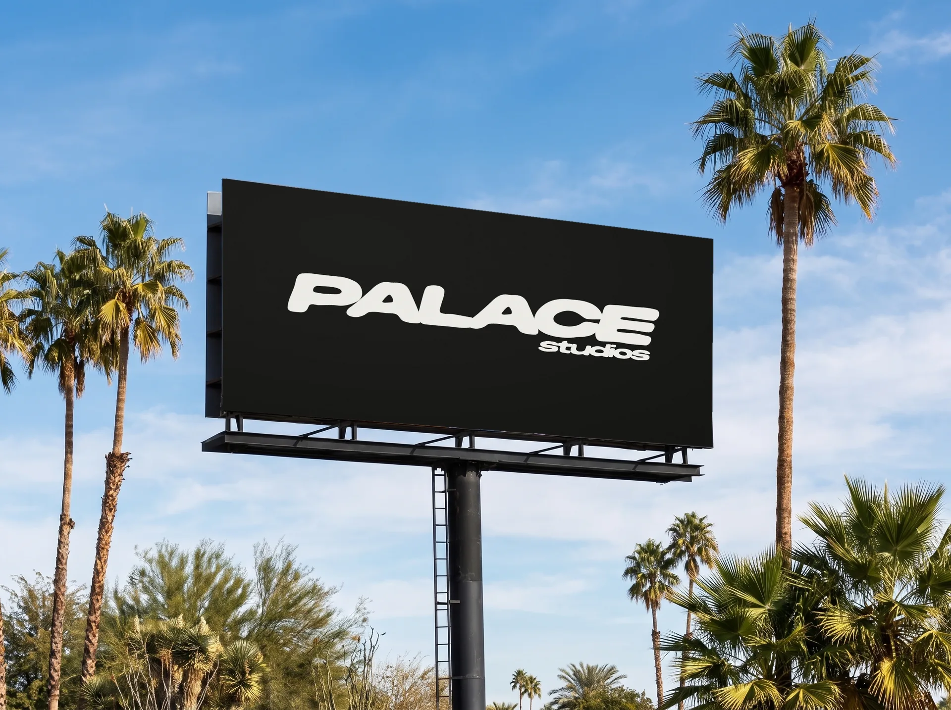 A Palace Studios billboard against blue sky and palm trees